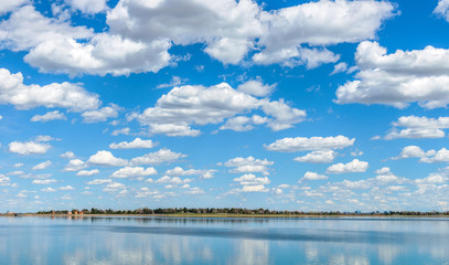 Spring Clouds - White spring clouds, on blue sky, rolling pass a city lake. Marston Lake, Denver-Lakewood, Colorado, USA.