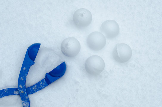 Blue plastic clip snowball fight tool device with snowballs on pure snow background