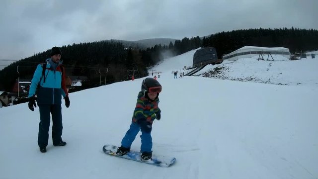 Little boy learns to ride a snowboard.
Father and son enjoy a winter day in the mountains. Stabilized video.