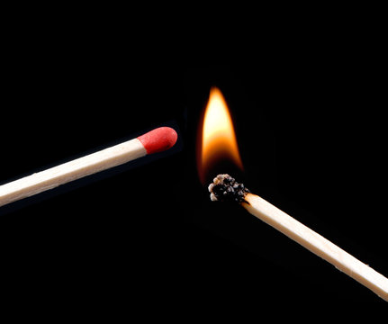 Cerillo encendido encendiendo otro. Llama