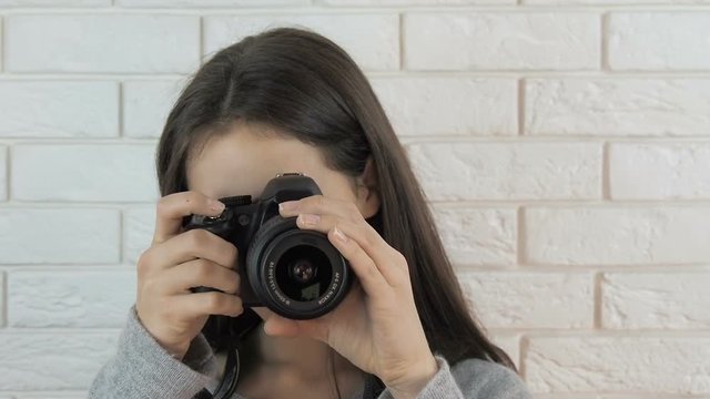 The girl is a photographer. Beautiful teen girl taking pictures with camera.