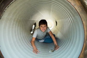 Beautiful young boy dressed in blue and gray playing in slide - toboggan 
