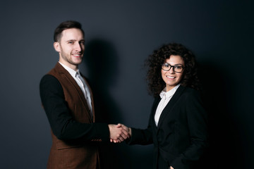 handshake between business partners, man and girl on a dark background