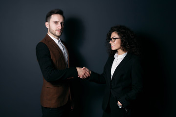 successful transaction between a man and a woman. handshake on a dark background