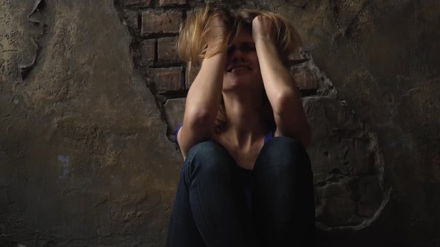 Beaten girl screaming and crying while sitting on the floor