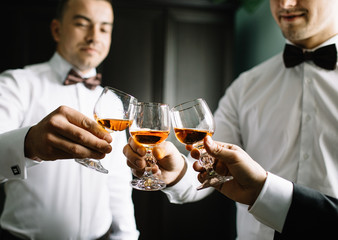 stylish groomsmen helping happy groom getting ready in the morning