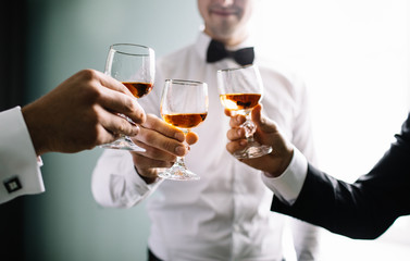 stylish groomsmen helping happy groom getting ready in the morning