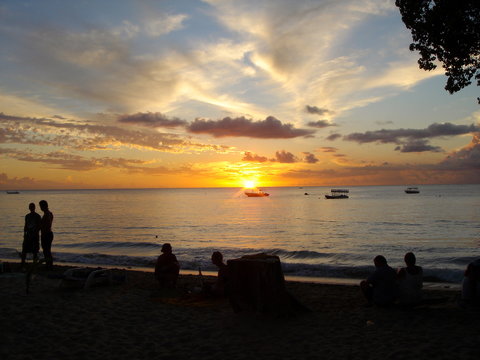 Sunset in Barbados with silhouette of people enjoying drinks on the beach