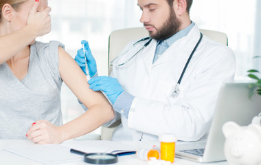 Vaccination. Flu shot. Doctor injecting flu vaccine to patient's arm