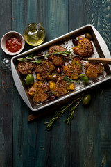 Baked potatoes cooked in baking tray with herbs, salt, oil and spices. Step homemade recipe. From above food dark wooden background.