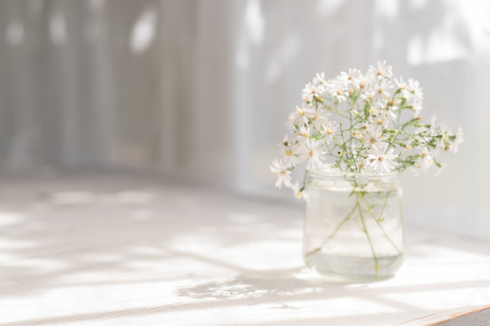 Small white flowers in a glass jar.