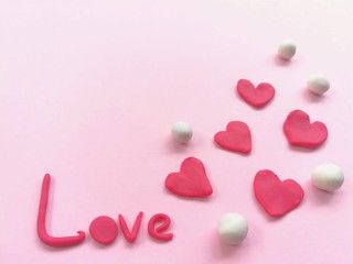 Beautiful red heart and love word made from plasticine clay on pink paper background, sweet color dough