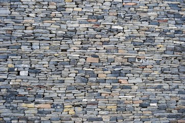 Old faux stacked grey stone wall with neat chiseled edge. Background texture of an ancient Chinese stone wall.