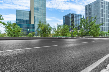 empty asphalt road near glass office building.