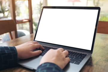 Mockup image of hands using and typing on laptop with blank white desktop screen on wooden table in cafe