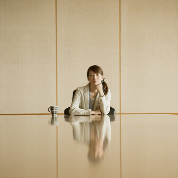 会議室で頬杖をつくビジネスウーマン