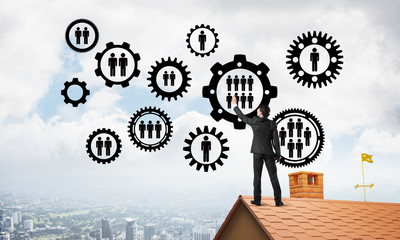 Businessman on house roof presenting teamwork and connection concept. Mixed media