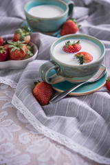 Fresh strawberries and cup of milk on a tablecloth.