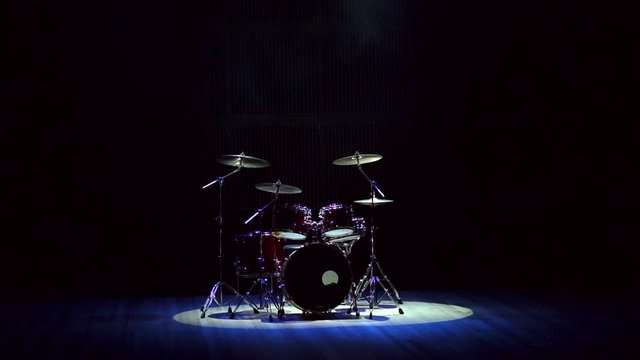 Drum set on a black background on stage. Modern drum set on stage in the dark with the spotlight.