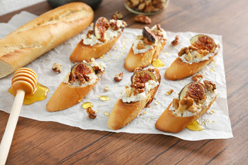 Delicious baguette toasts with fig on wooden table
