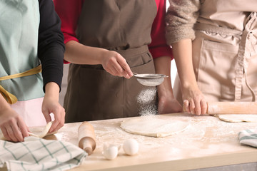 Obraz na płótnie Canvas Young women preparing dough for pastries on kitchen table