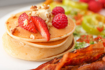 Delicious pancakes with fried bacon on plate, closeup