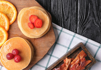 Delicious pancakes with fried bacon served for breakfast on wooden table