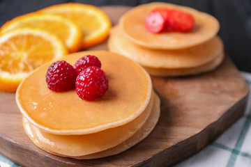 Delicious pancakes with berries on wooden board, closeup