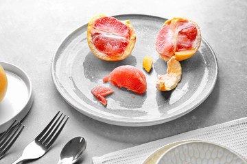 Ceramic plate with grapefruit on grey background