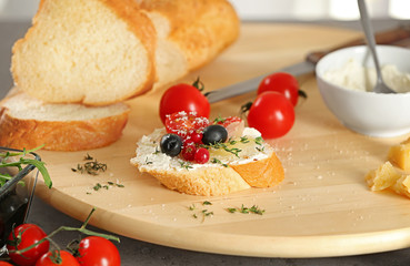 Tasty bruschetta with olives and cherry tomatoes on wooden board, closeup