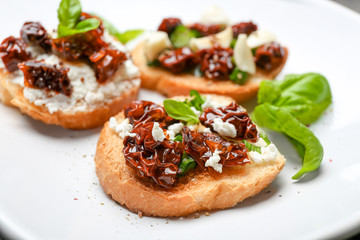 Tasty bruschetta with sun-dried tomatoes on plate, closeup