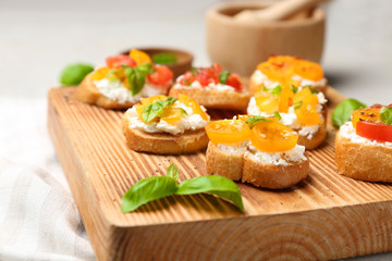 Tasty bruschettas with tomatoes on wooden board