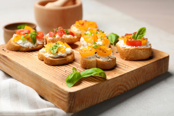 Tasty bruschettas with tomatoes on wooden board