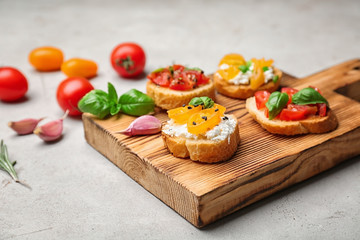 Tasty bruschettas with tomatoes on wooden board, closeup