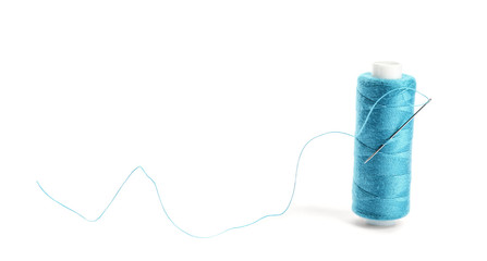 Spool of sewing thread with needle on white background