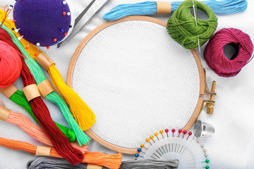 Colorful threads and embroidery hoop with fabric, top view