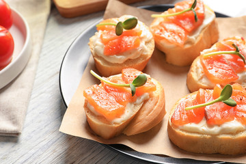 Tasty bruschettas with salmon on plate, closeup
