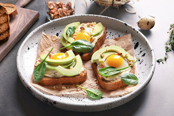 Tasty bruschettas with fried eggs and avocado on plate