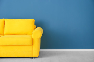 Bright yellow couch near color wall - obrazy, fototapety, plakaty