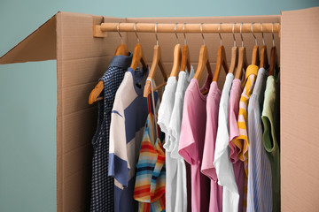 Wardrobe box with clothes on color background, closeup