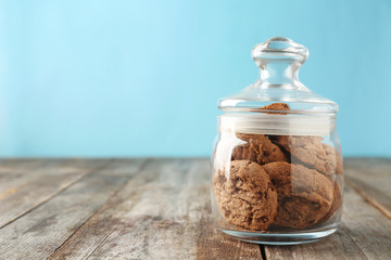 Delicious oatmeal cookies with chocolate chips in glass jar on wooden table