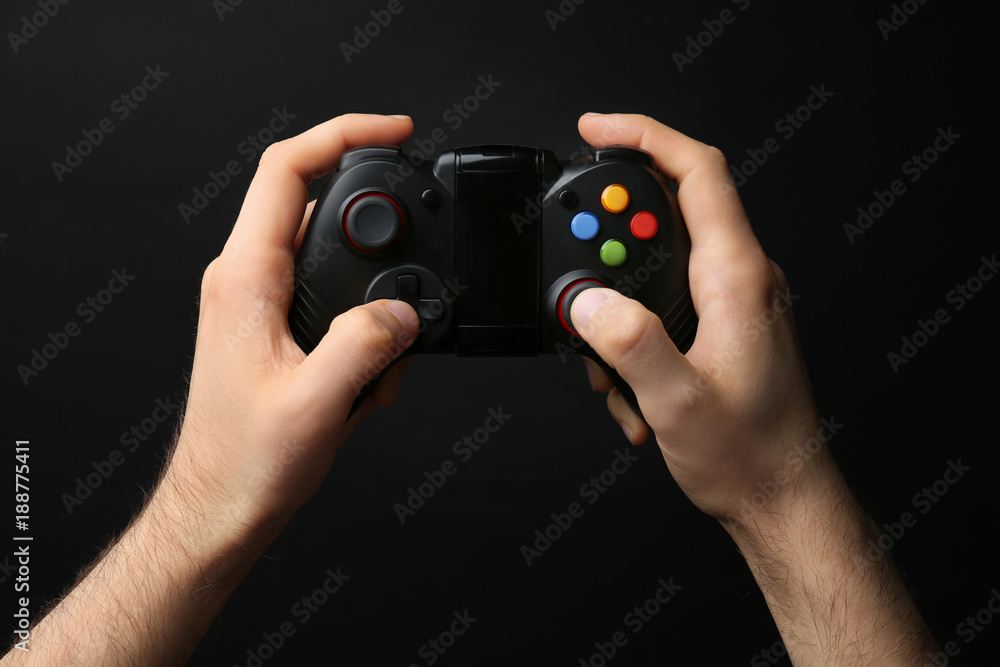 Wall mural man holding video game controller on black background