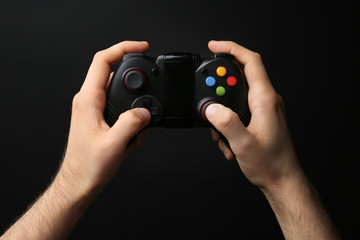 Fototapeta premium Man holding video game controller on black background
