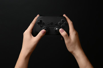 Woman holding video game controller on black background © Africa Studio