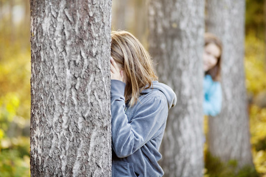 Girls playing hide and seek in forest