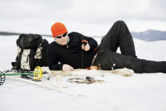 Man lying on snow and fishing
