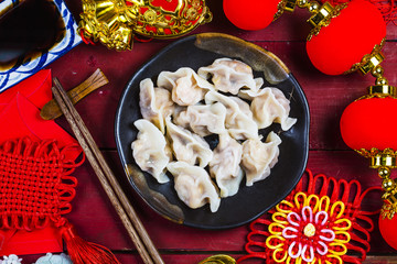 Chinese Jiaozi new year food, spring festival food on traditional spring festival Spring festival atmosphere and dumplings, ang pow or red packet and gold ingots. Chinese characters means luck,wealth