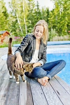 Blonde woman sitting on jetty with cat