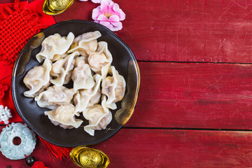 Chinese Jiaozi new year food, spring festival food on traditional spring festival Spring festival atmosphere and dumplings, ang pow or red packet and gold ingots. Chinese characters means luck,wealth