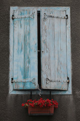 Beautiful blue and white stained wooden shutters and red flower box